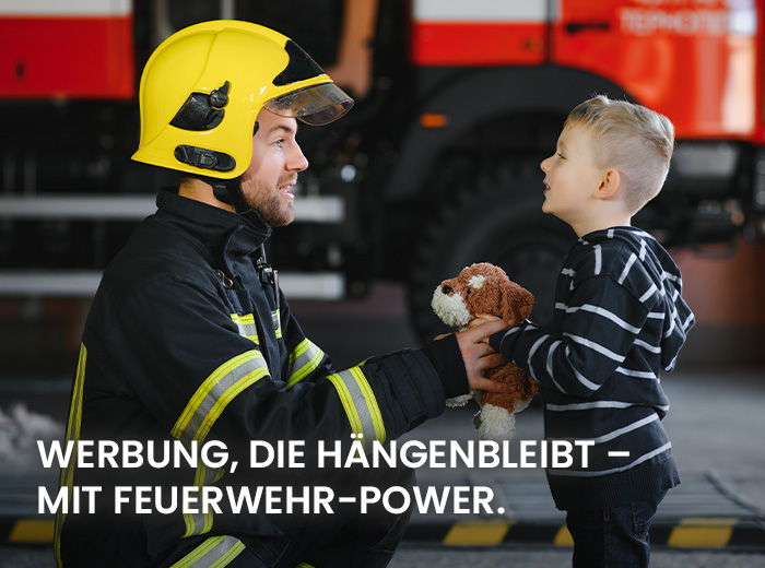 Werbemittel: ein Feuerwehrmann gibt einem kleinen Jungen einen Plüschbär Werbemittel: ein Feuerwehrmann gibt einem kleinen Jungen einen Plüschbär